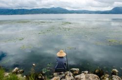 阴沉天空渔民钓鱼湖面对面的山阴沉的天空高清图片